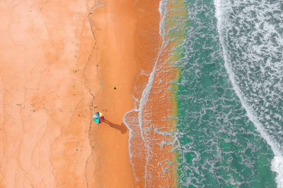 distant unrecognizable person on sandy coast of wavy ocean