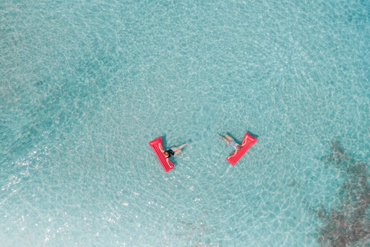 people lying on an inflatable floater on the beach
